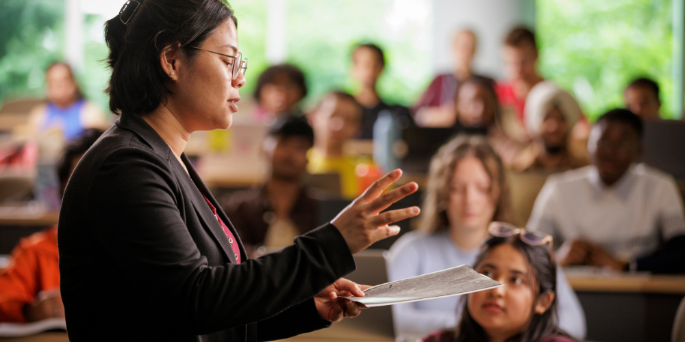 A professor lectures in a full classroom