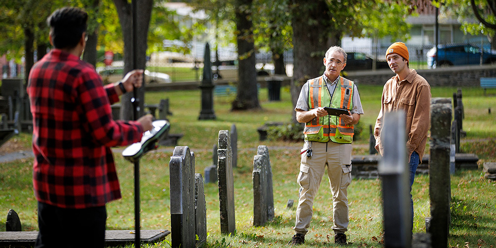 A professor and students are examining an old cemetery.