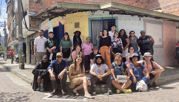 A photo of faculty and student participants in the Colombia field school in 2023. They are at an urban street corner, with some people sitting and some standing behind them.