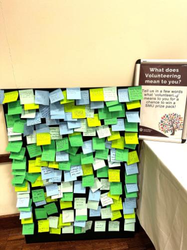 Photo from the 2024 Volunteer Fair showing a display board covered with colorful Post-it notes. Each note contains handwritten messages from students sharing what volunteering means to them.