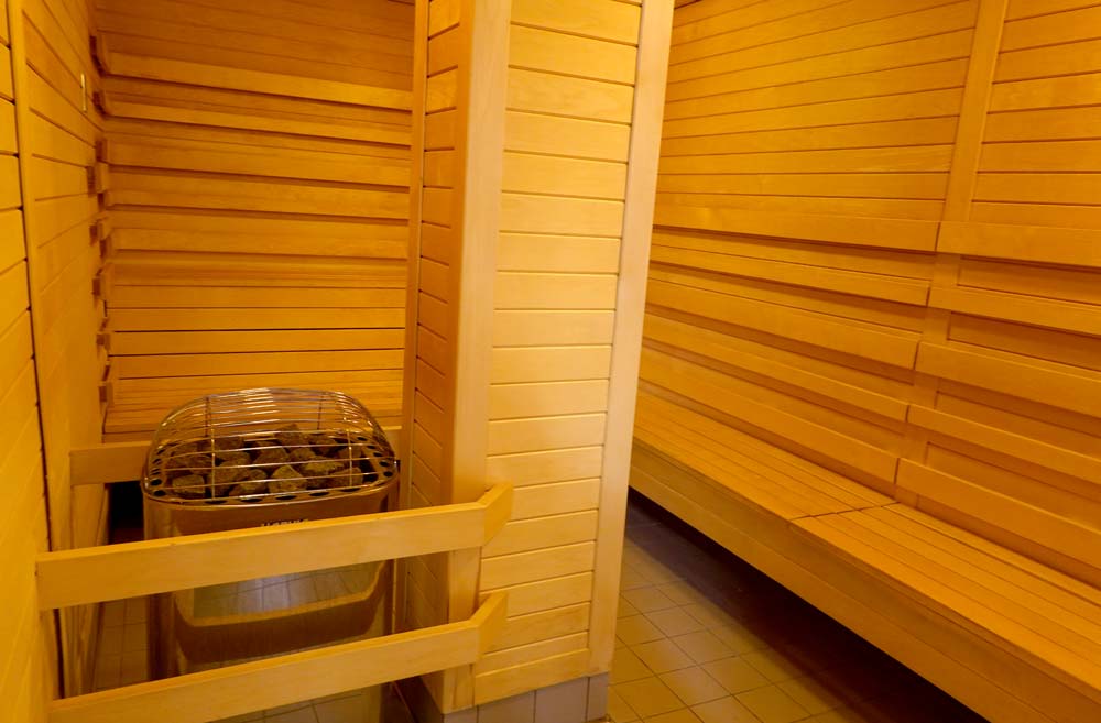 Sauna in low light with sauna stove on the left and benches to the right.