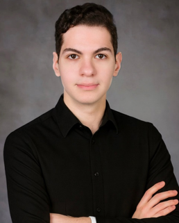 A man wearing a dark shirt, posing professionally for a photo