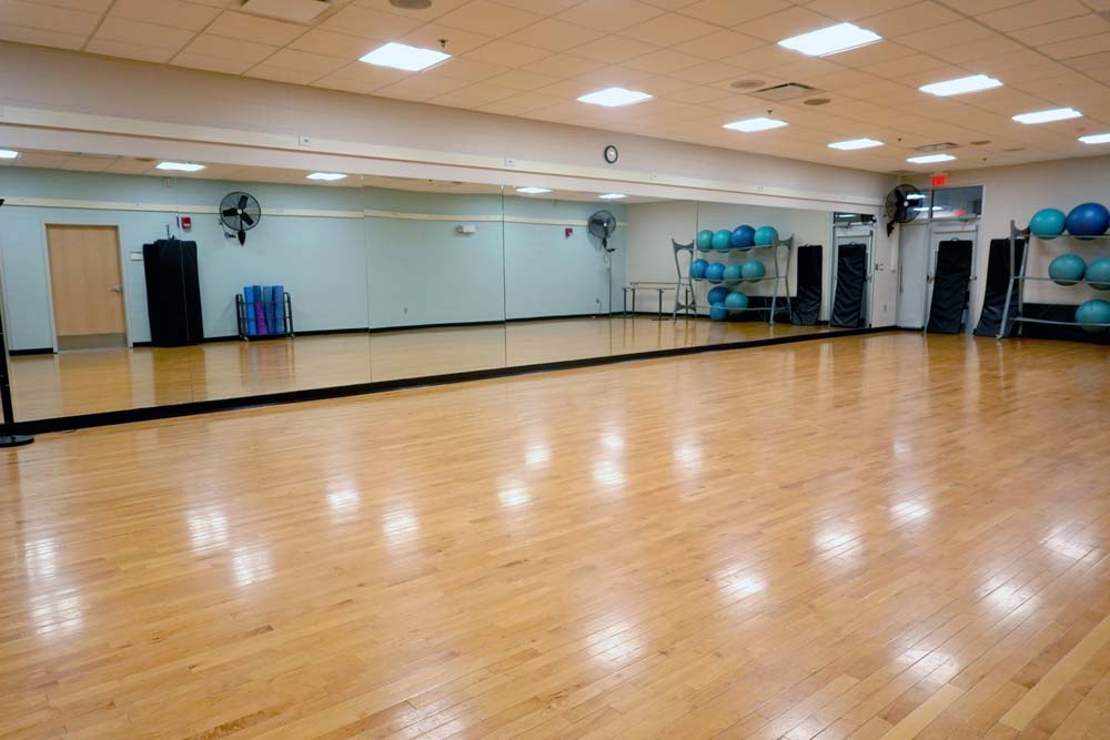 Studio A. Dance style studio with hardwood floor and mirrored wall to the left.