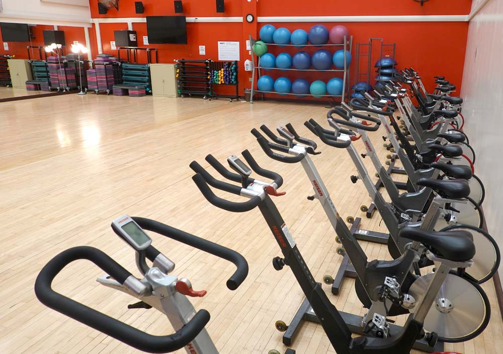 Studio C. Large dance style studio with spin bikes lined up along the side wall and fitness equipment against the back wall
