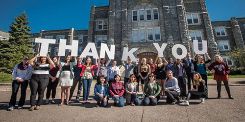 Students in front of the McNally building holding letters that spell thank you.