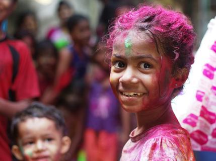 Portrait of a young girl with her hair covered in vibrant pink and purple powder during the Hindu festival of Holi