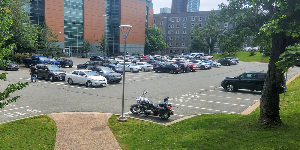 
Cars and a motorcycle in a parking lot near the Science building.