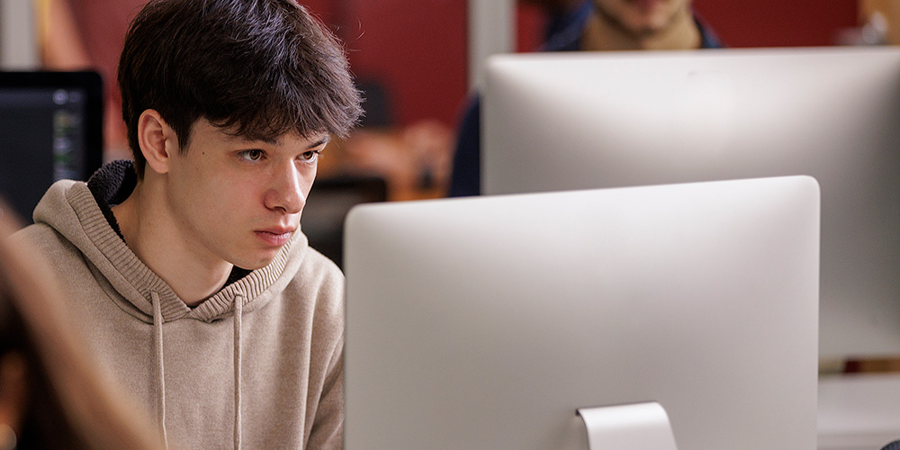 A computer science student is working on a computer.